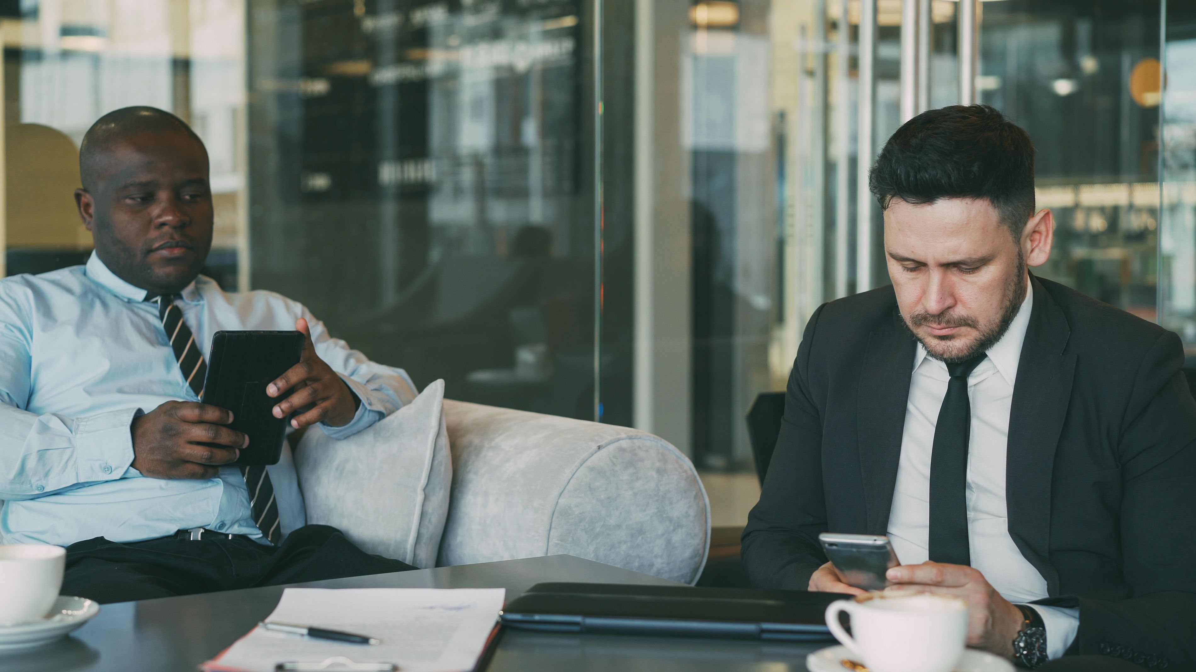 business men using mobile devices in office lounge