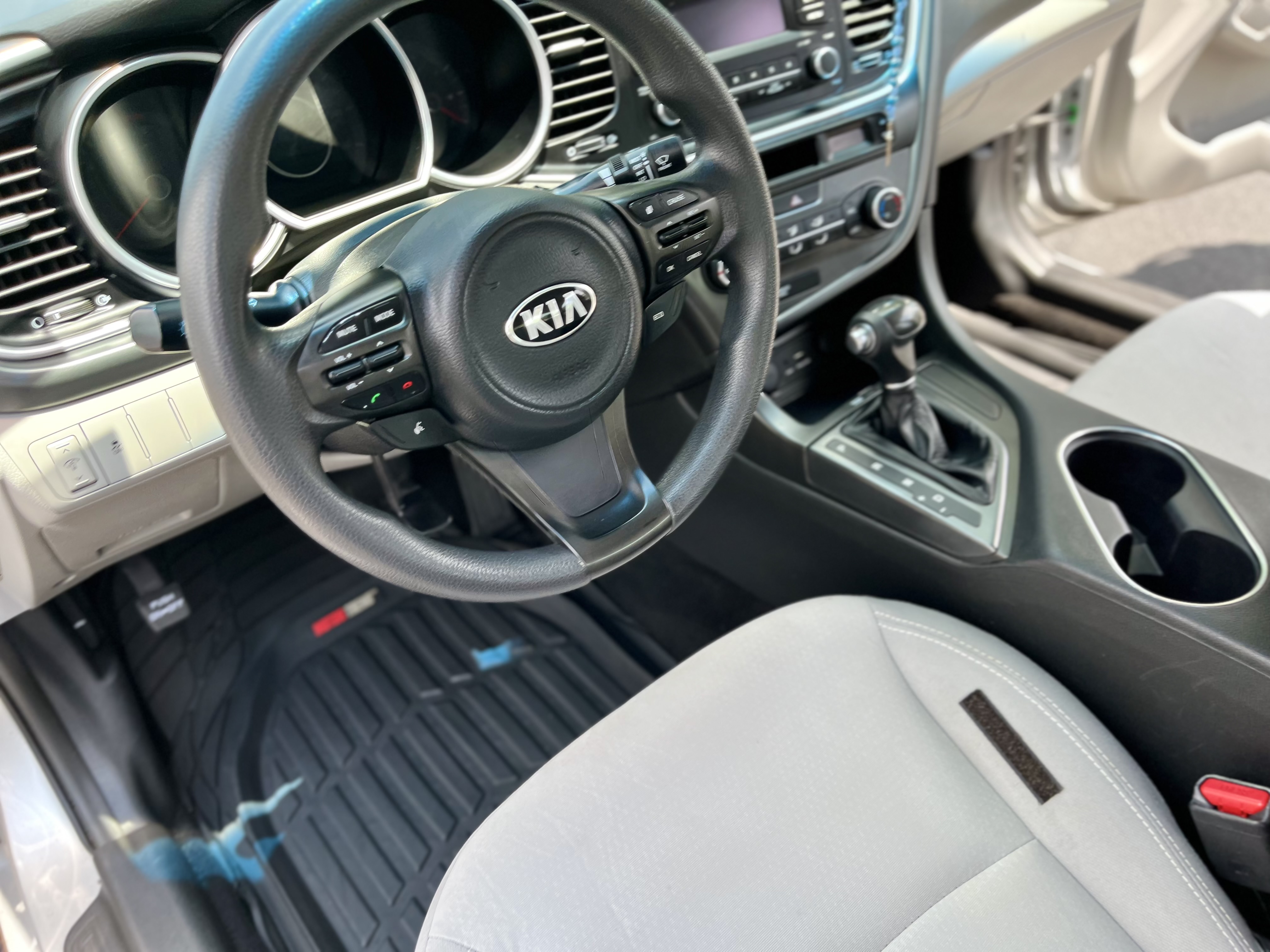 Clean Kia vehicle interior showing the steering wheel, dashboard, center console, and gray front seat after detailing.