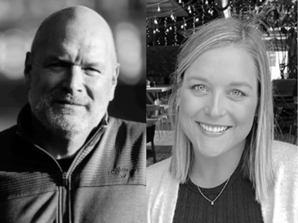 A black and white image features a bald man with a beard on the left and a smiling woman on the right.