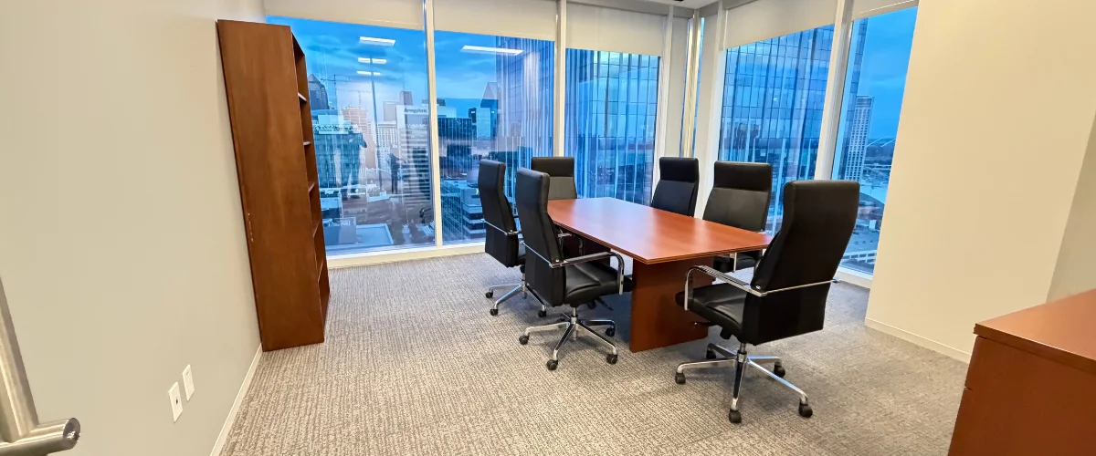 A modern corporate conference room featuring a large wooden table, six black executive chairs, and expansive city views. A modern corporate conference room featuring a large wooden table, six black executive chairs, and expansive city views.