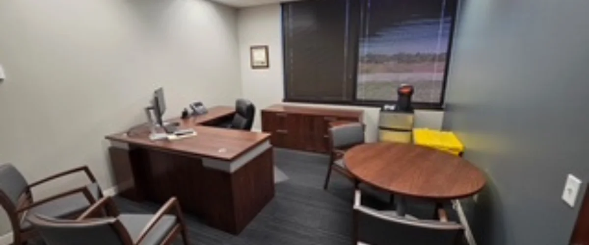 A modern office features a wooden U-shaped desk, an executive chair, side chairs, and a round meeting table, with a large window. A modern office features a wooden U-shaped desk, an executive chair, side chairs, and a round meeting table, with a large window.