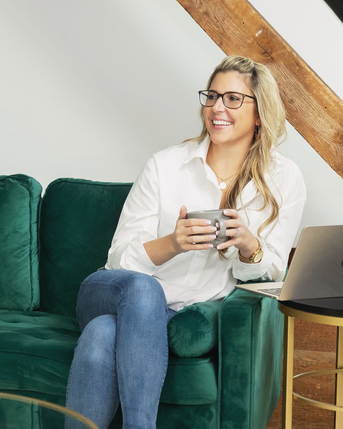 Carissa Hetrick laughing on a green sofa with a laptop