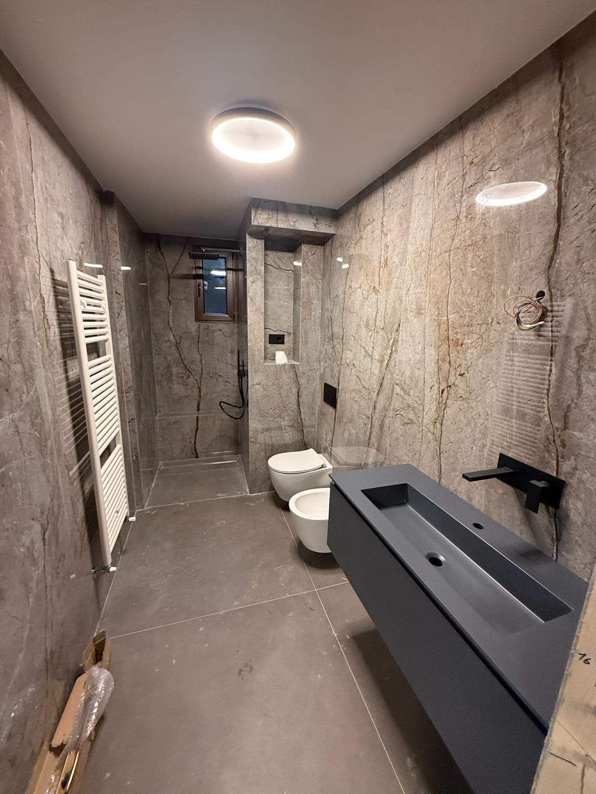 Bagno ristrutturato con marmo grigio e doppi sanitari sospesi