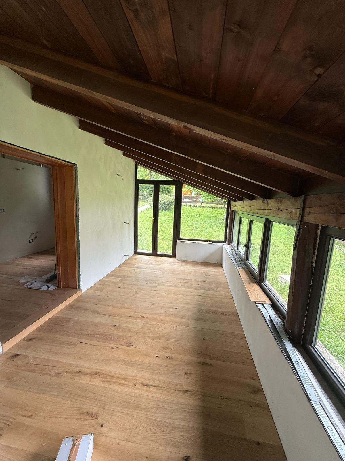 Ampio sottotetto ristrutturato con travi a vista e parquet, vista sul giardino