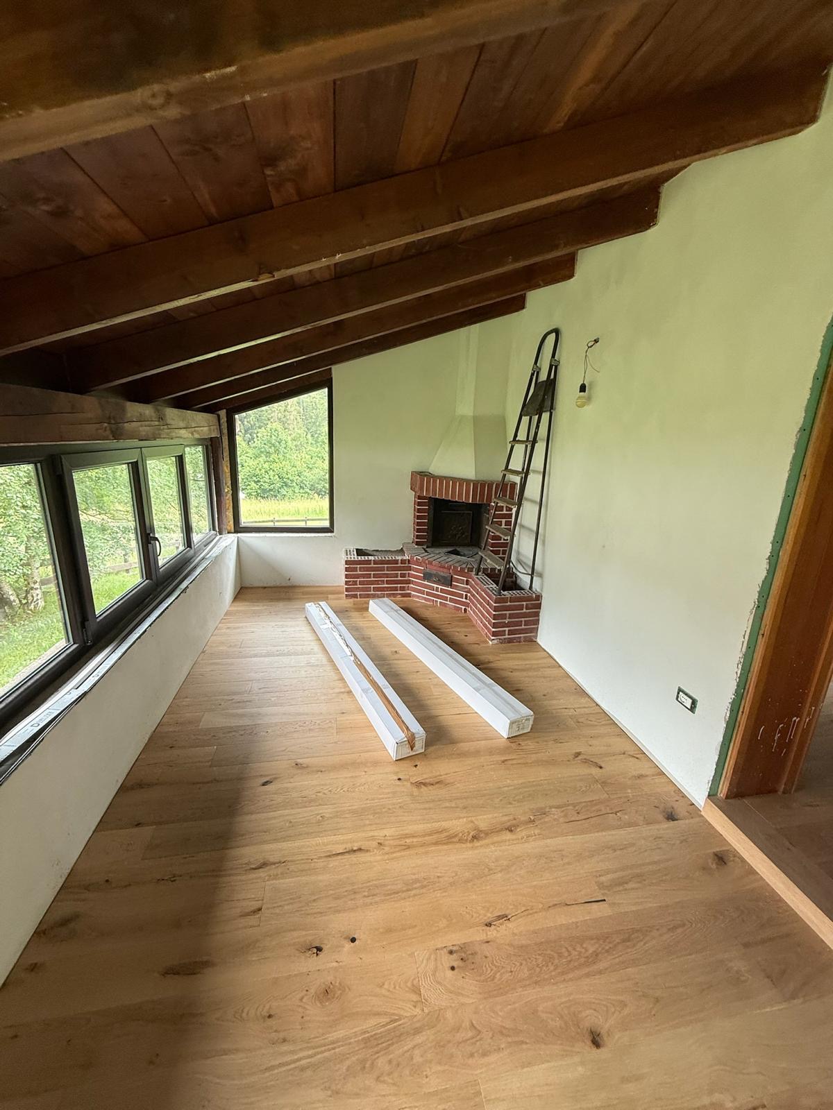 Mansarda ristrutturata con camino in mattoni a vista e travi in legno