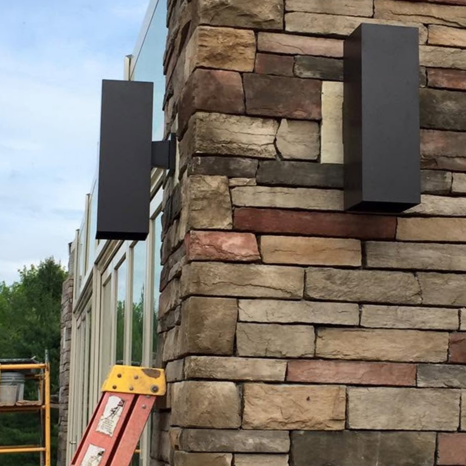 Modern exterior wall sconces mounted on a stone facade