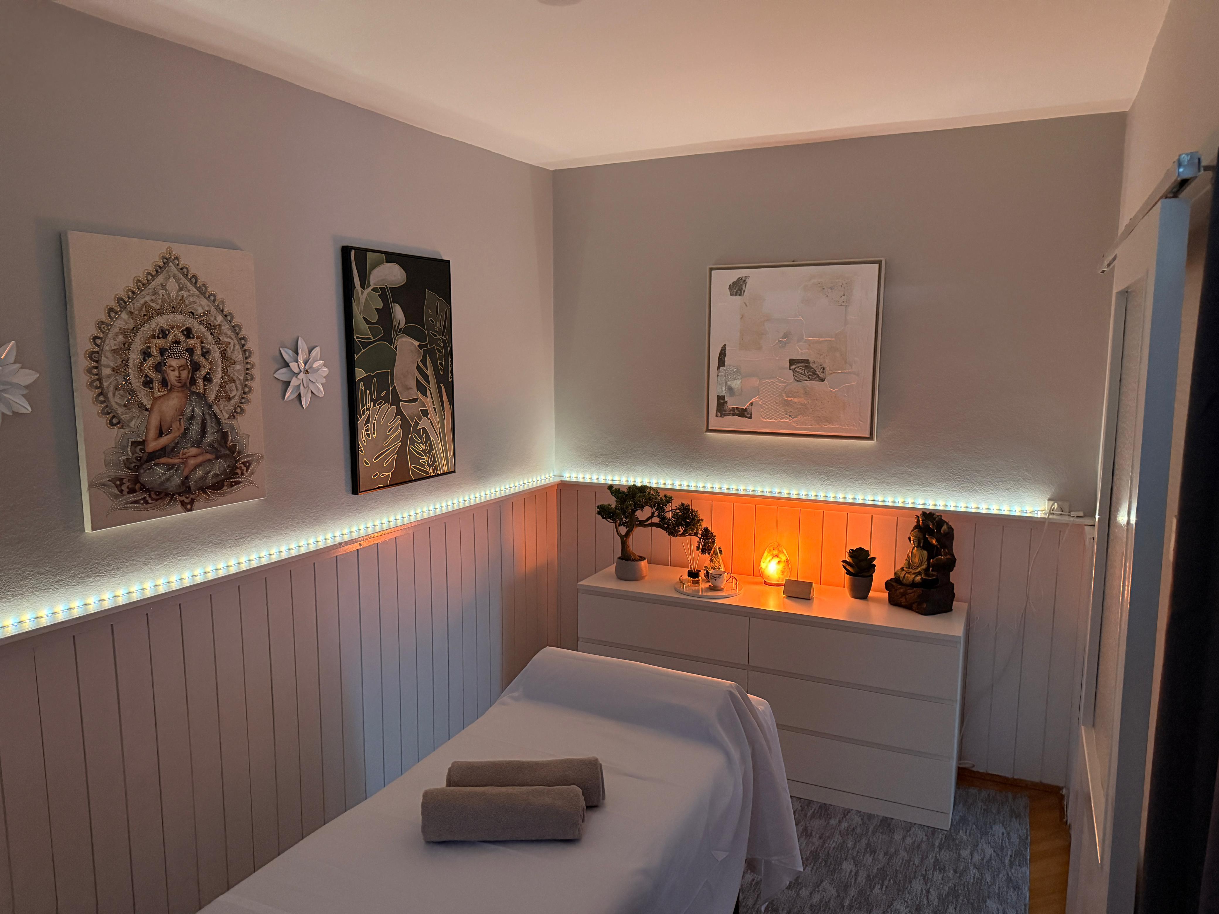 A draped massage table in a dark green studio touched by warm light