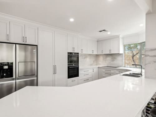 Kitchen renovation with white cabinetry and white stone benchtops in a modern Australian home