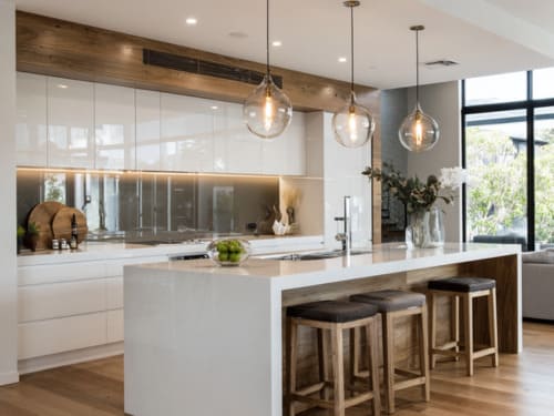 Modern Australian kitchen with white cabinetry, timber accents, and a kitchen island with stools