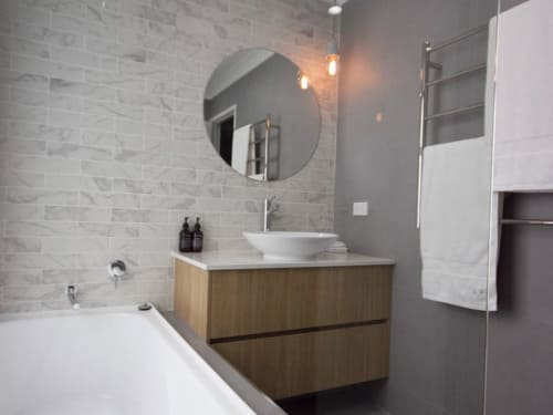 Elegant bathroom renovation with subway tile feature wall, single sink, and timber vanity cabinetry