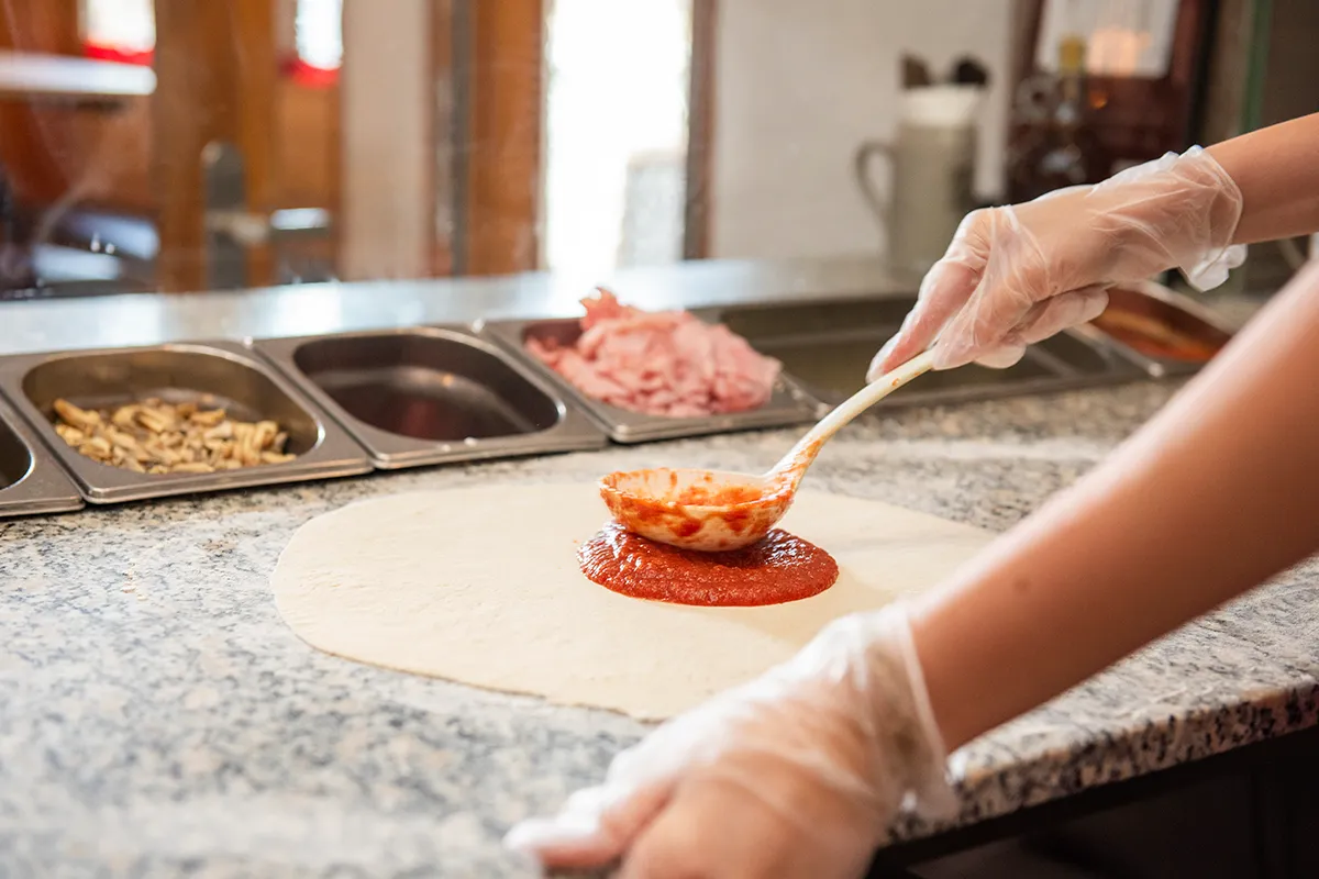 Frische Tomatensoße wird auf der Pizza verteilt