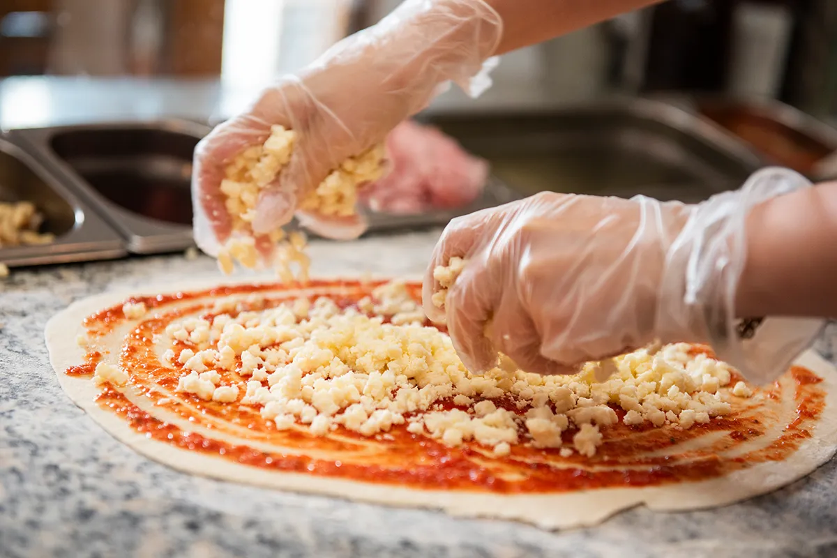 Frische Zutaten und Belag werden auf der Pizza platziert