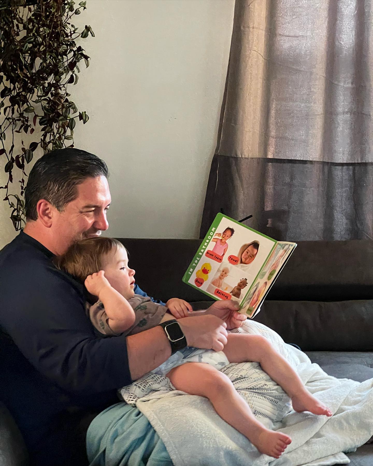 Sean Hyde reading a picture book to his baby