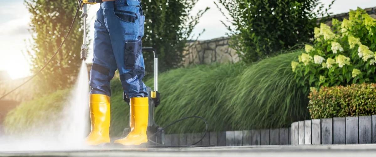 man pressure washing patio