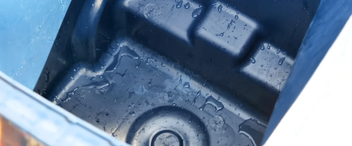 Close-up of clear water droplets on the deep blue textured interior of a plastic storage bin.