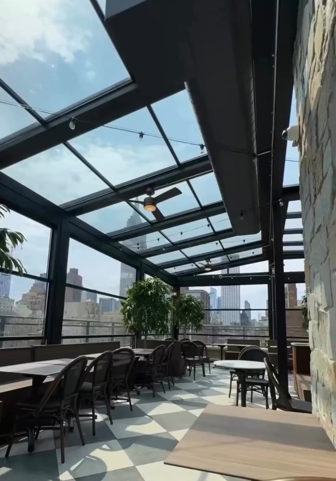 Daylight rooftop dining space beneath a glass roof
