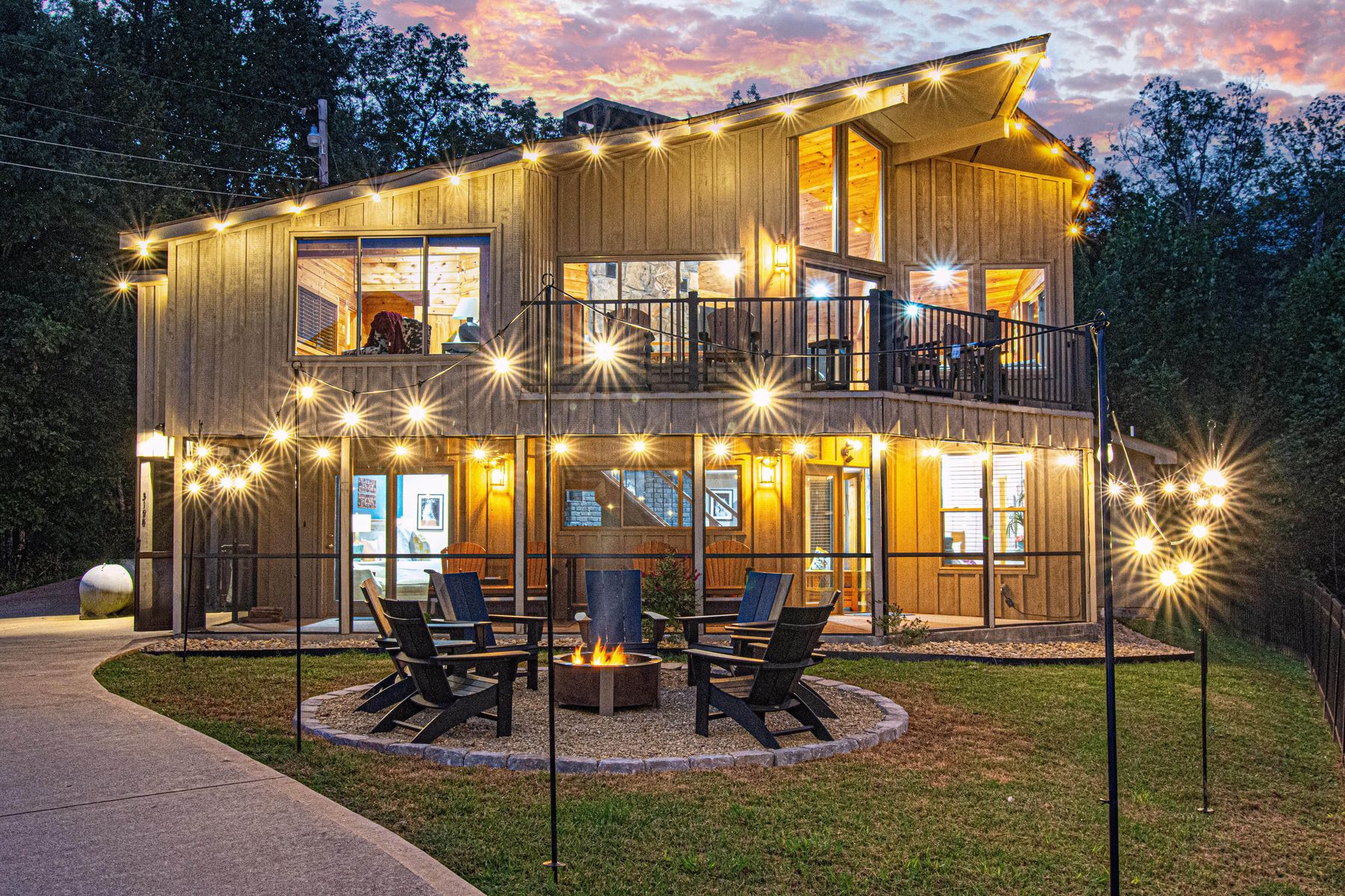 Birdsong Ridge lit up at night, string lights glowing over the fire pit