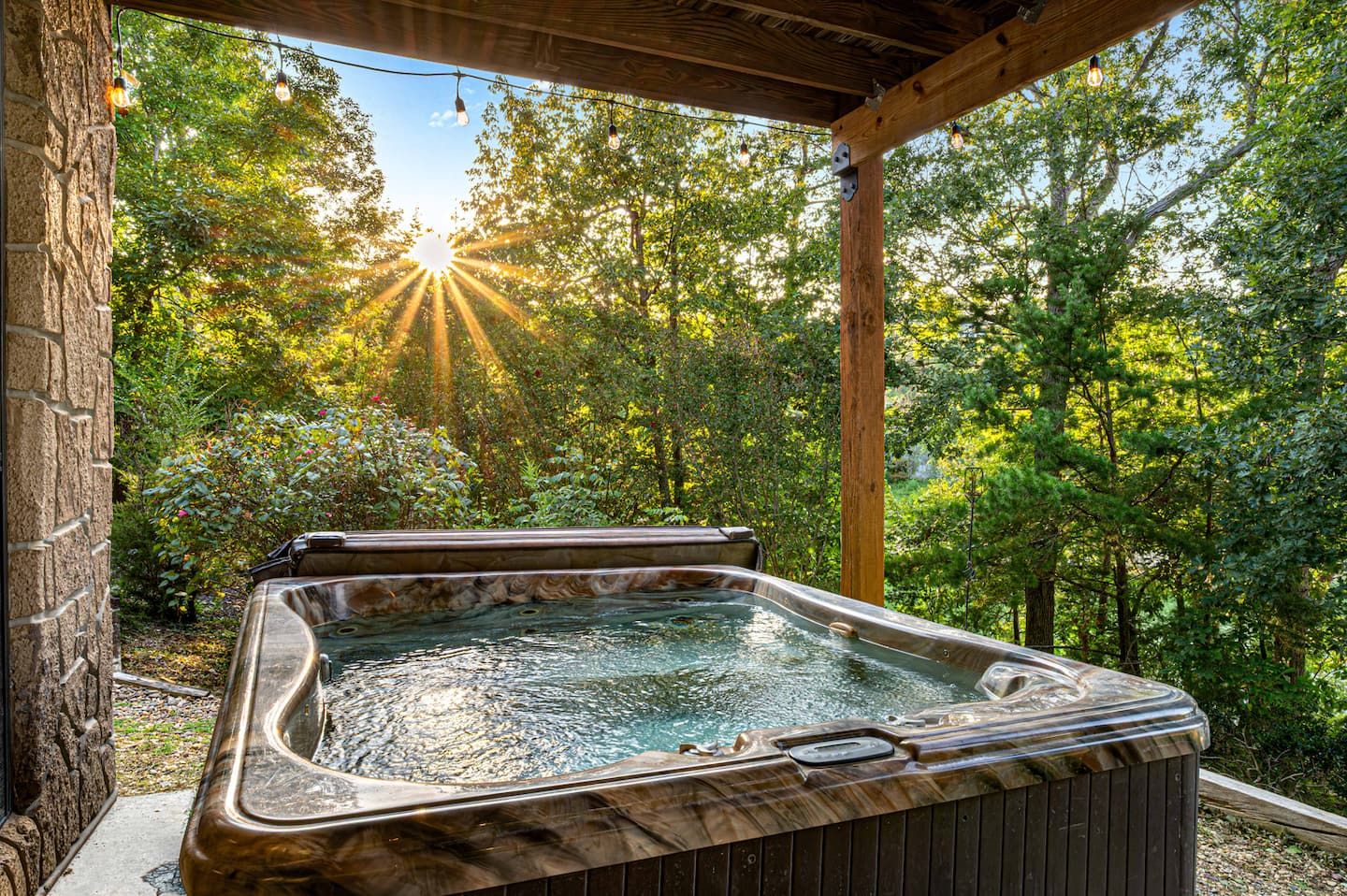 The hot tub sits on the covered lower porch, tucked into the trees. Nobody plans this part. You just end up here.