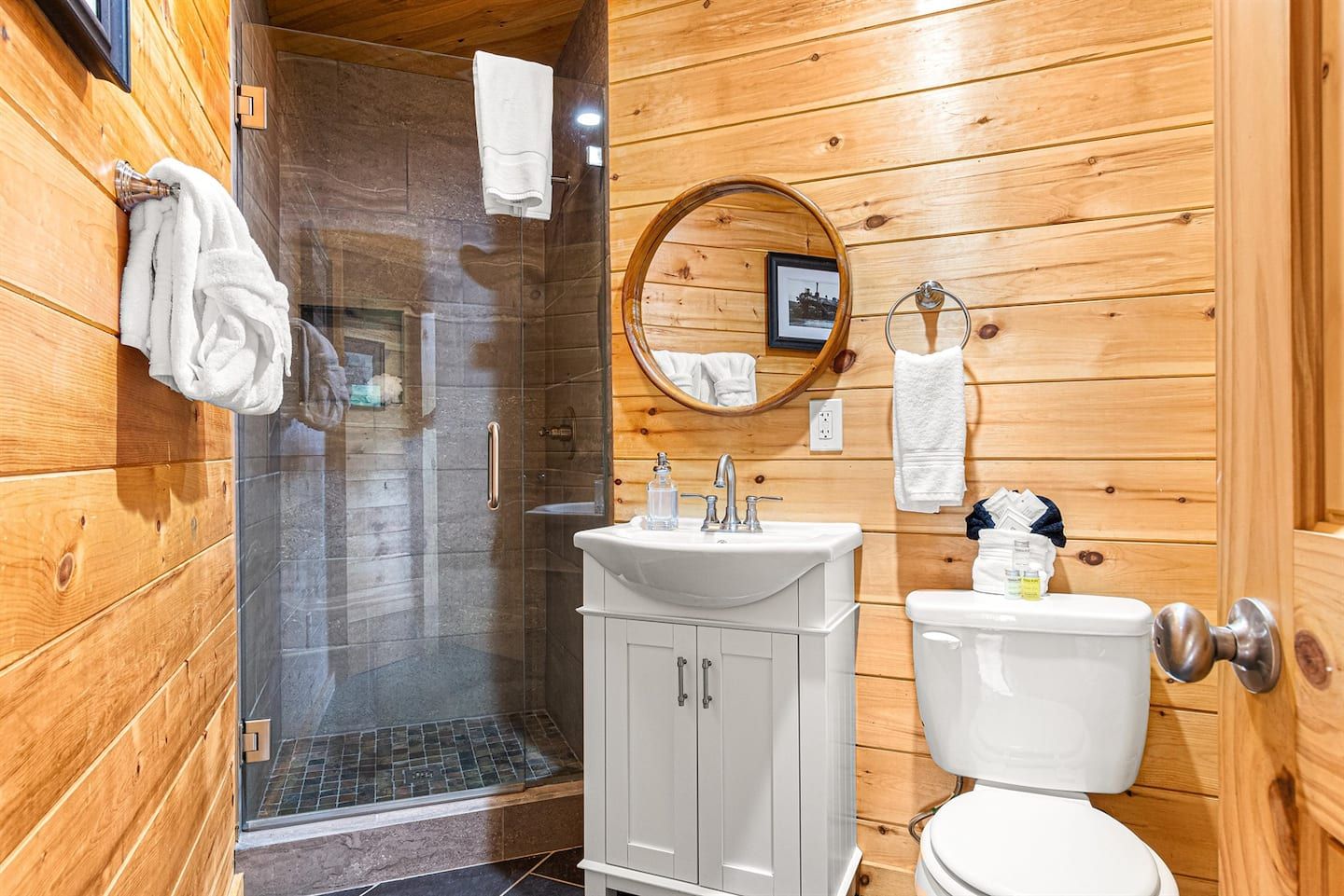 Tucked away in the upstairs hallway, this charming bathroom is functional and stylish. It features a slate walk-in shower and a vanity, perfect for refreshing in a cozy setting. This space reflects thoughtful design throughout the chalet.