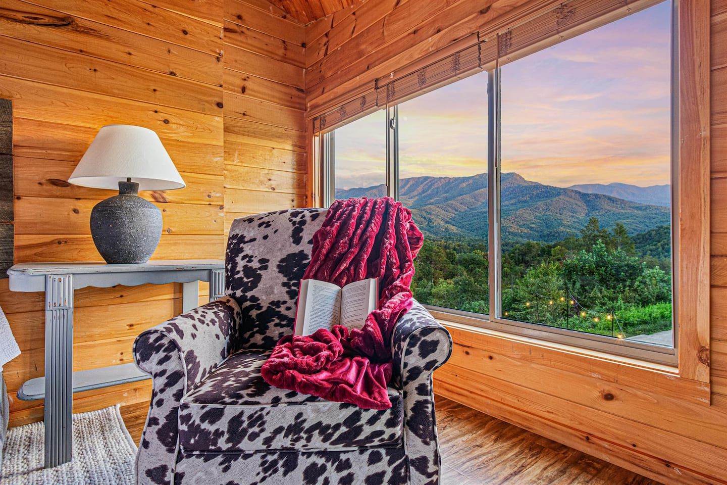 The upper level master bedroom frames an unobstructed panoramic view of the Smoky Mountains through large windows — wake up to this every morning. Soft morning light, the ridgeline stretching before you, and nowhere you need to be.