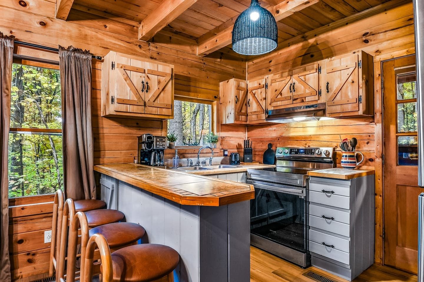 The kitchen opens to views of the surrounding woods, filling the space with soft, natural light. It’s warm and welcoming — the kind of place where mornings start slowly and conversation feels easy.