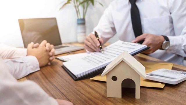 a-person-signing-a-real-estate-contract-with-a-small-wooden-house-model-on-the-table a-person-signing-a-real-estate-contract-with-a-small-wooden-house-model-on-the-table