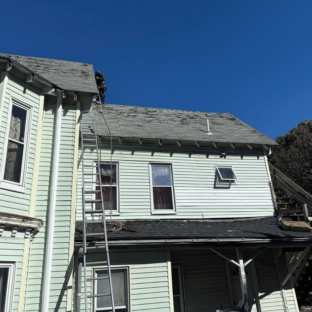 roof inspection in Melrose MA showing asphalt shingles and technician assessing roof condition