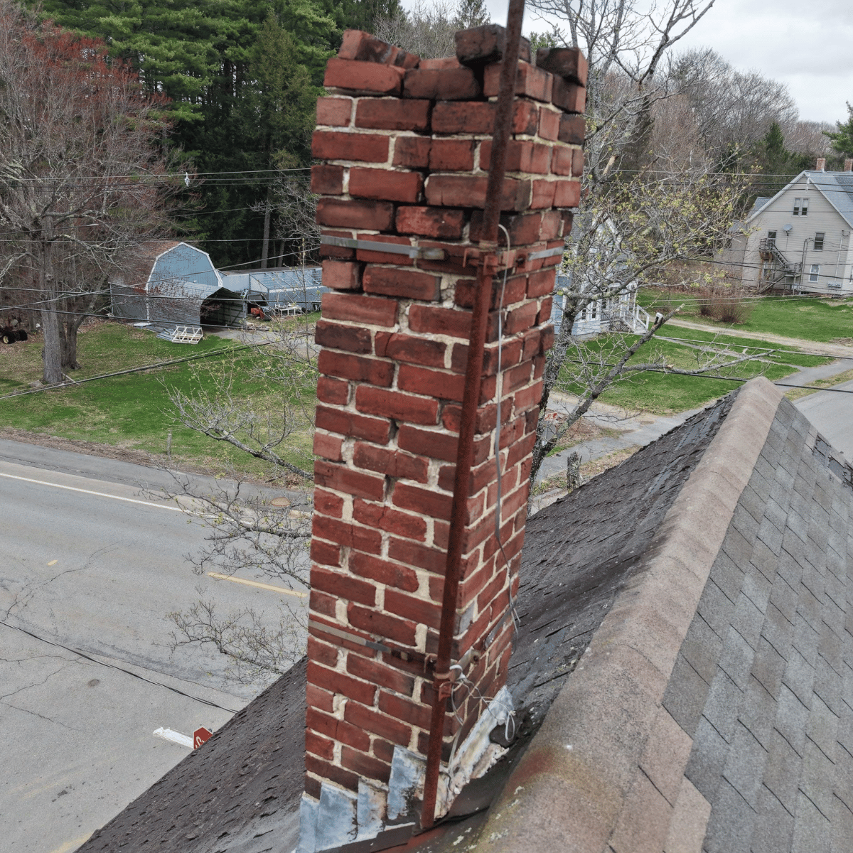 Leaning chimney structure on roof indicating potential safety risk in Boston home