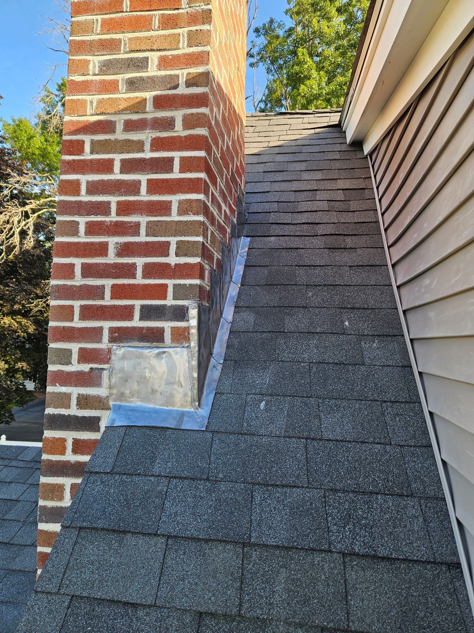 Brick chimney with step flashing installed to prevent roof leaks