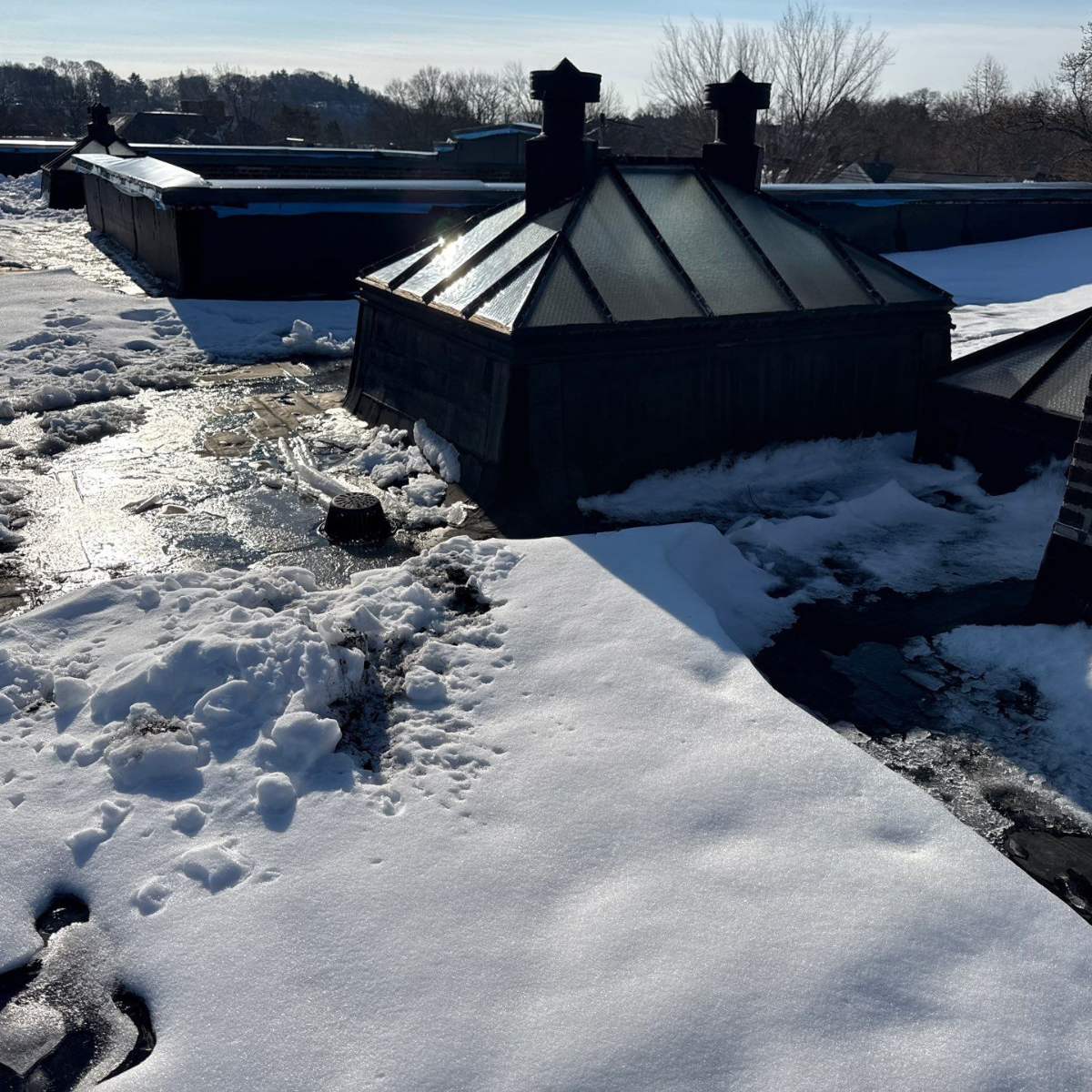 Ice dam removal process on a snow-covered residential roof