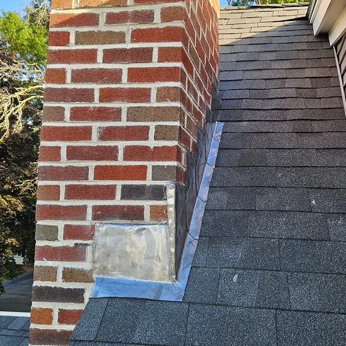 Brick chimney with step flashing installed to prevent roof leaks