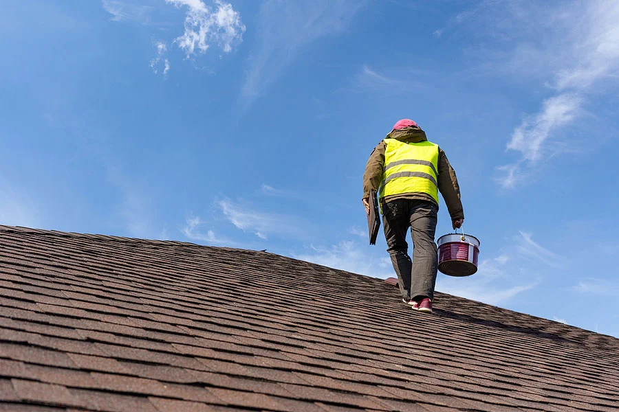 Roofing contractor inspecting an asphalt shingle roof for repair or replacement