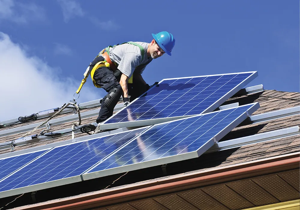 Technician removing solar panels before a roof replacement on a residential home in Massachusetts.