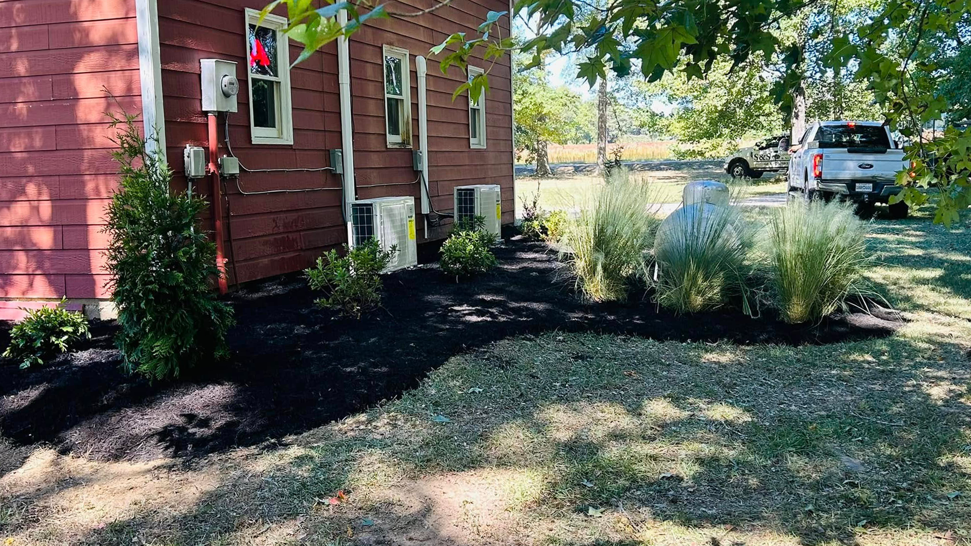 Mulch application and shrub pruning in a flower bed in Columbus, Mississippi