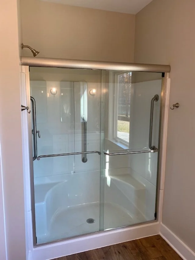 Custom-cut sliding glass door above fiberglass shower