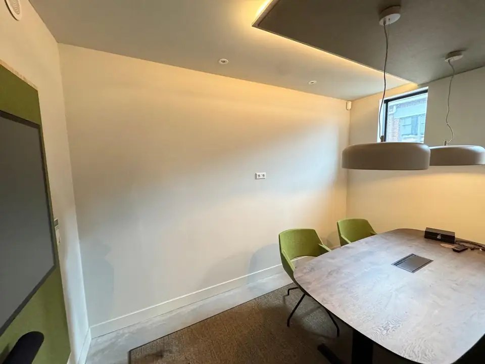 Besprekingsruimte van Flow Accountants vóór de installatie: een kale witte wand