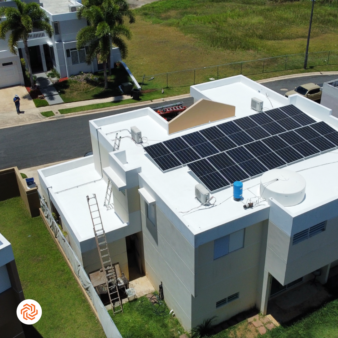 Familia latinx de cuatro personas sonriente en el patio con paneles solares en el techo visible al fondo, luz de tarde cálida, estilo fotográfico realista que transmite seguridad y ahorro familiar.