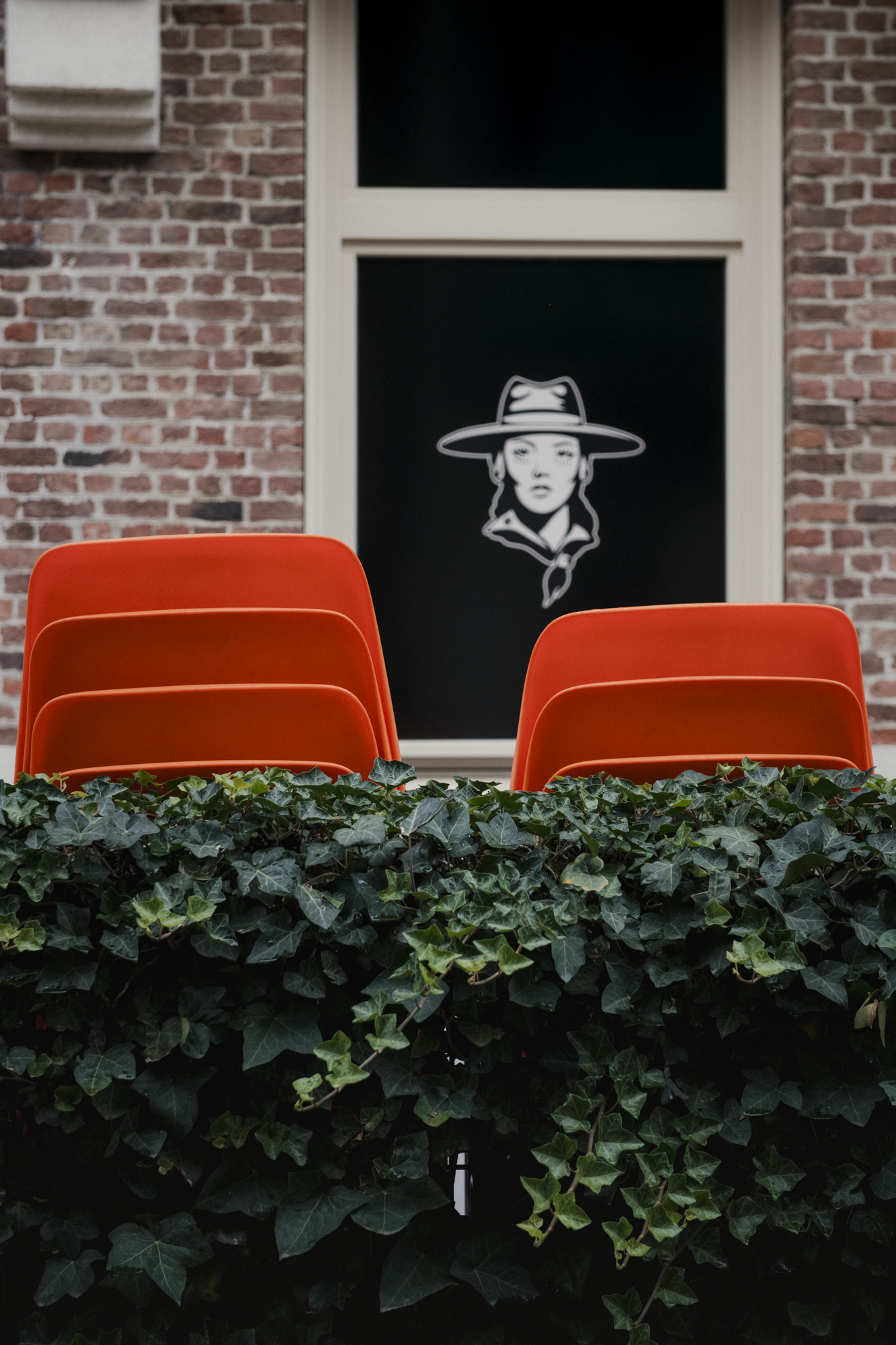 Gestapelde oranje stoelen en op achtergrond tekening vrouw met cowboyhoed 