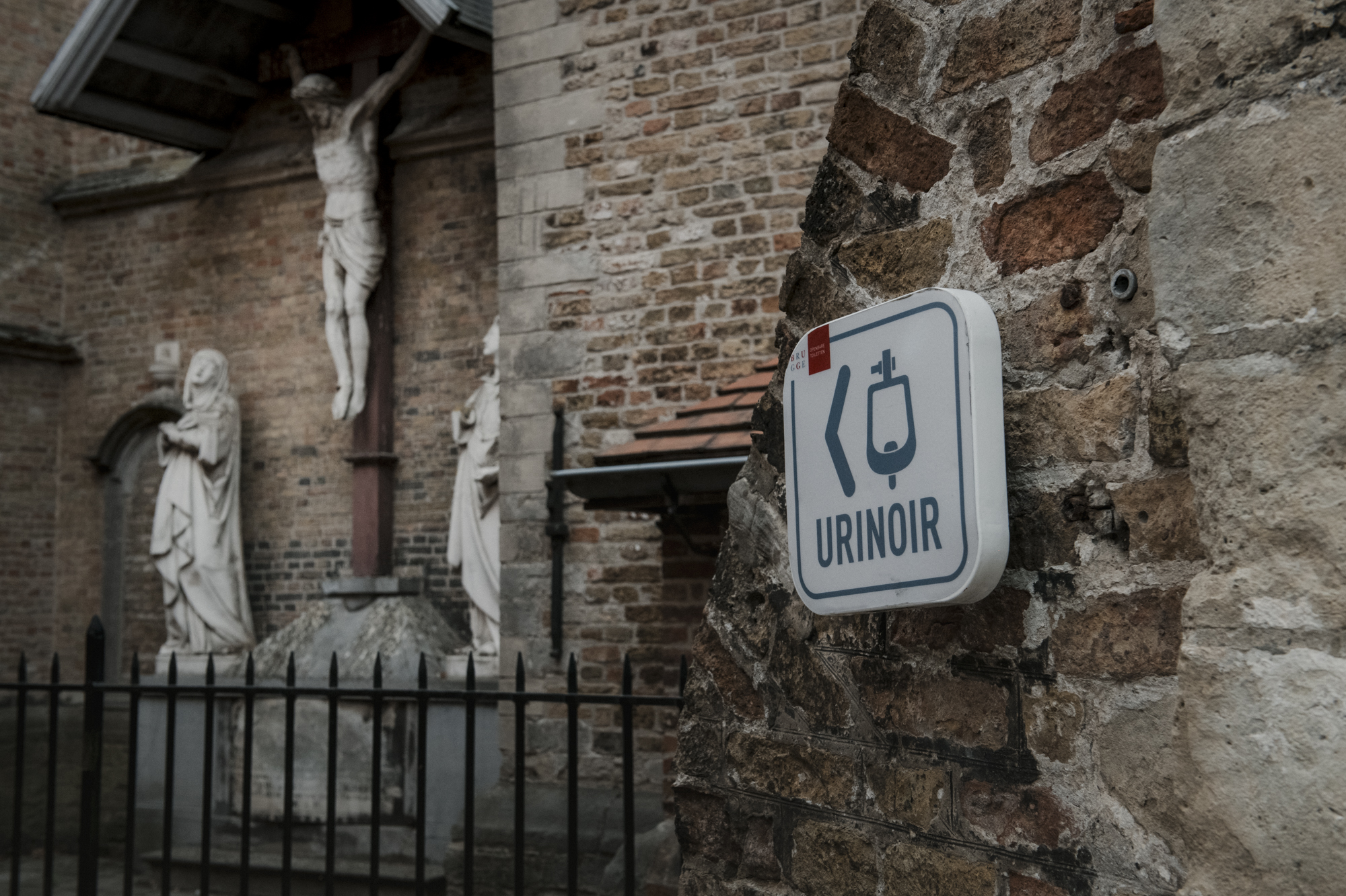 Urinoirbordje met heilige beelden op achtergrond in Brugge