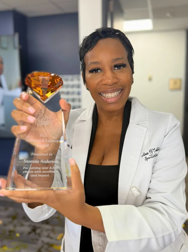 Stormie Anderson holding the Diamond Legacy Award for serving over 2,500 clients