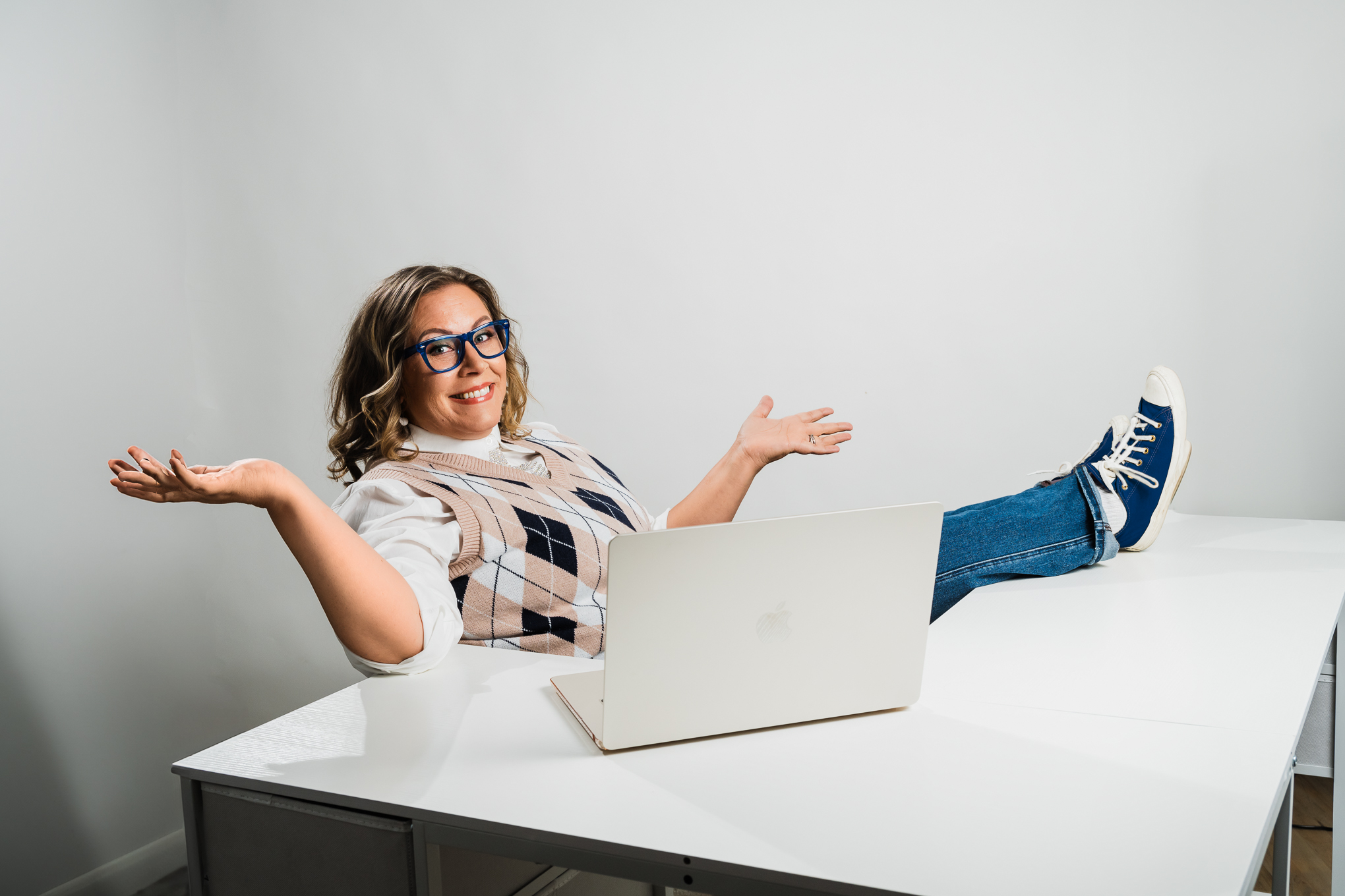Wendi leaning back at her desk, arms open, feet up, relaxed and ready
