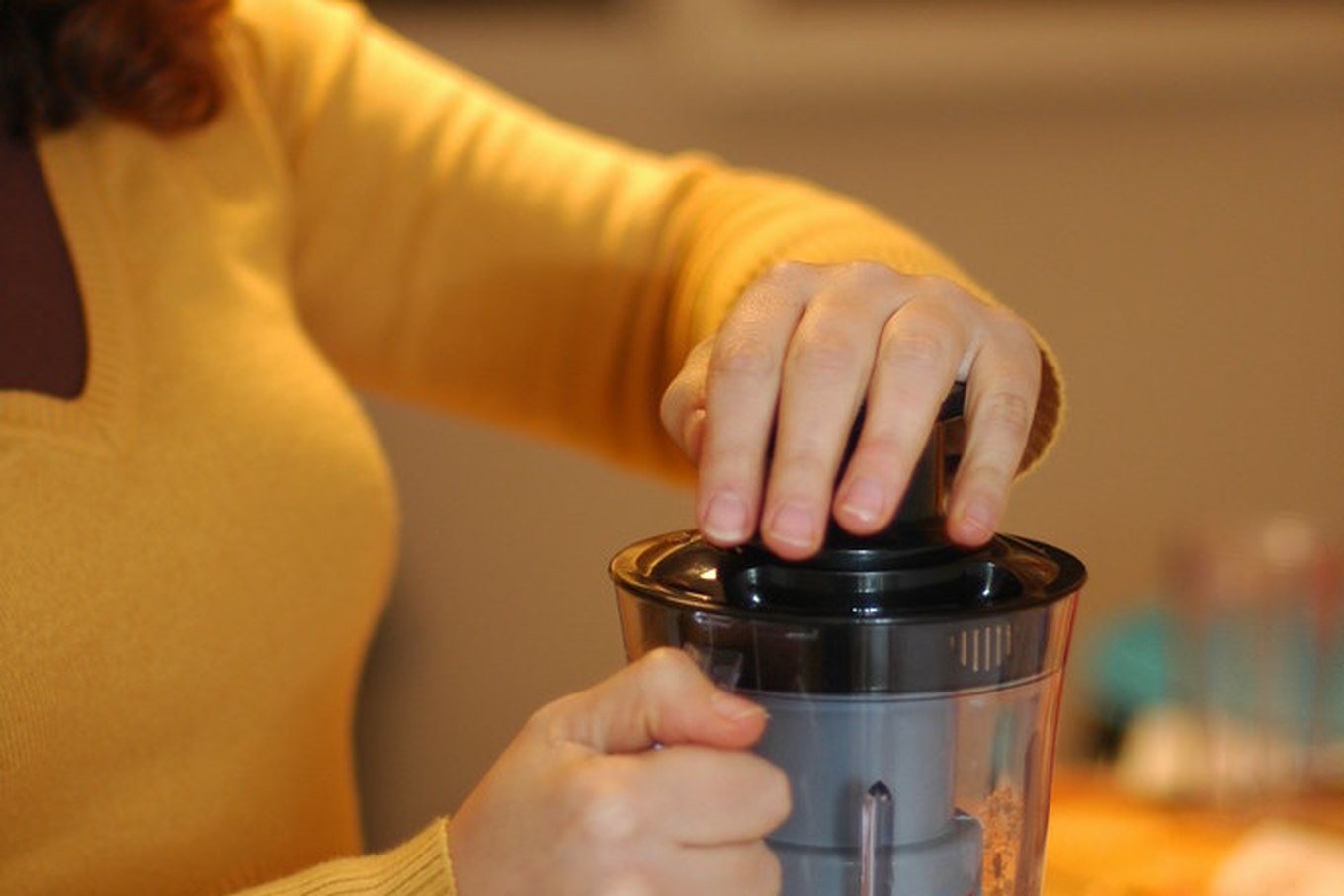 Hands operating a blender with ingredients in the jar, in a home kitchen