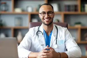médico con bata y  estetoscopio en el cuello sonriendo