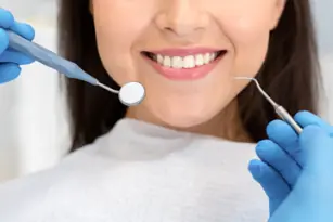 paciente de odontología sonriendo, espejo dental y herramiental dental