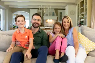 Familia de 4 personas sentados disfrutando la sala de su casa