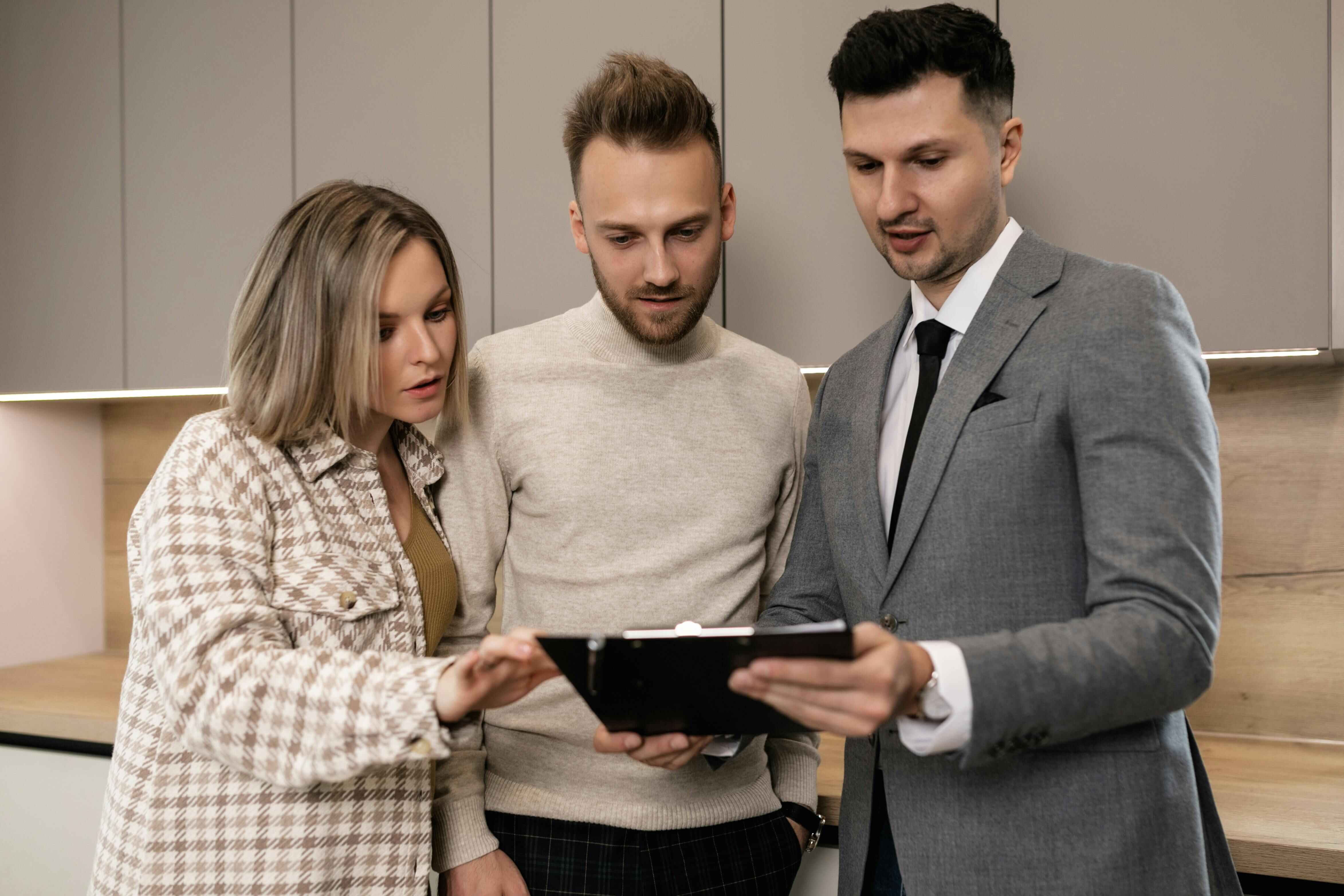 Buyer's agent presenting property documents and contract details to a young couple during a home inspection in Wollongong, New South Wales. Buyer's agent presenting property documents and contract details to a young couple during a home inspection in Wollongong, New South Wales.