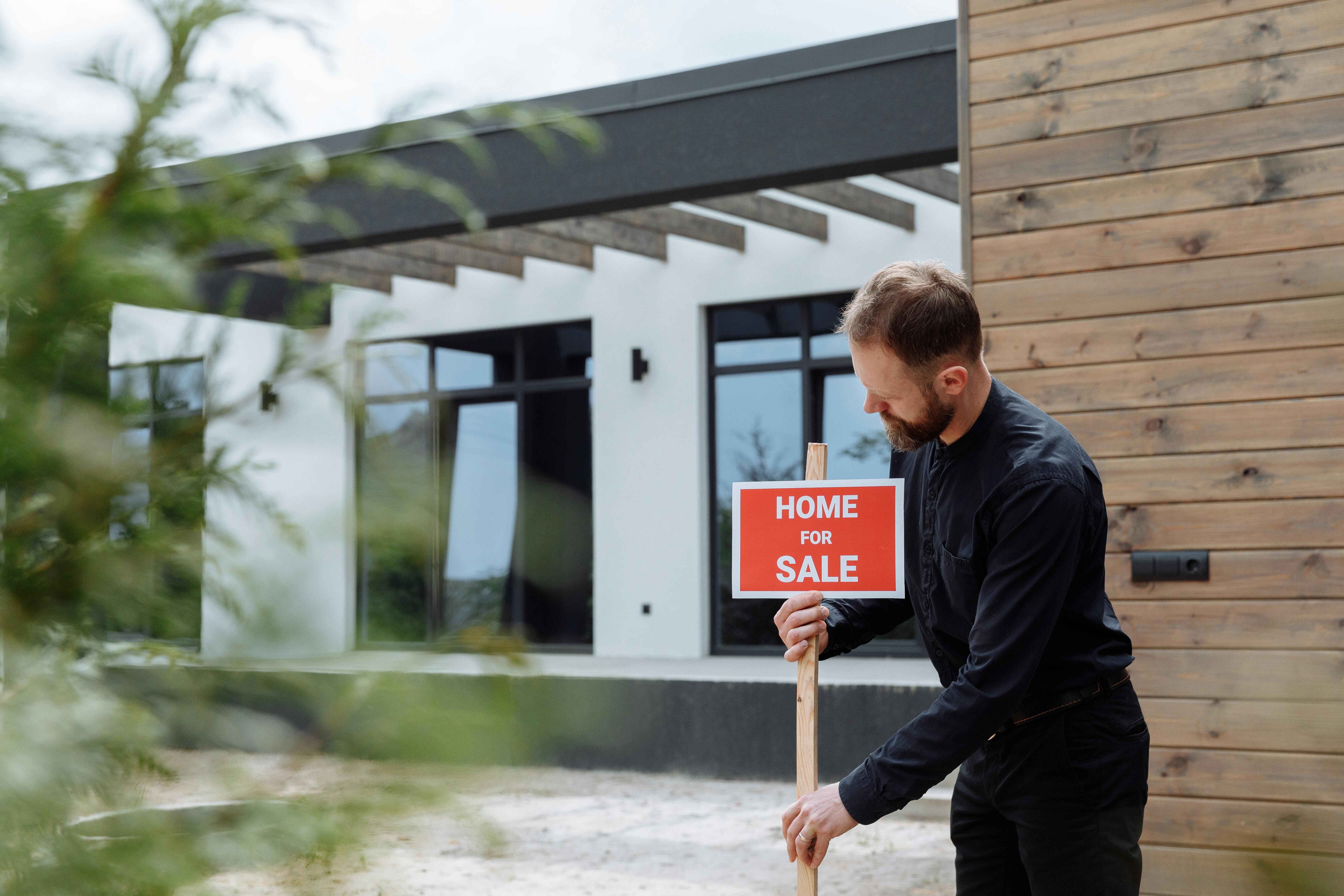 Real estate agent placing a Home For Sale sign outside a modern contemporary property in the Wollongong and Illawarra region of New South Wales. Real estate agent placing a Home For Sale sign outside a modern contemporary property in the Wollongong and Illawarra region of New South Wales.