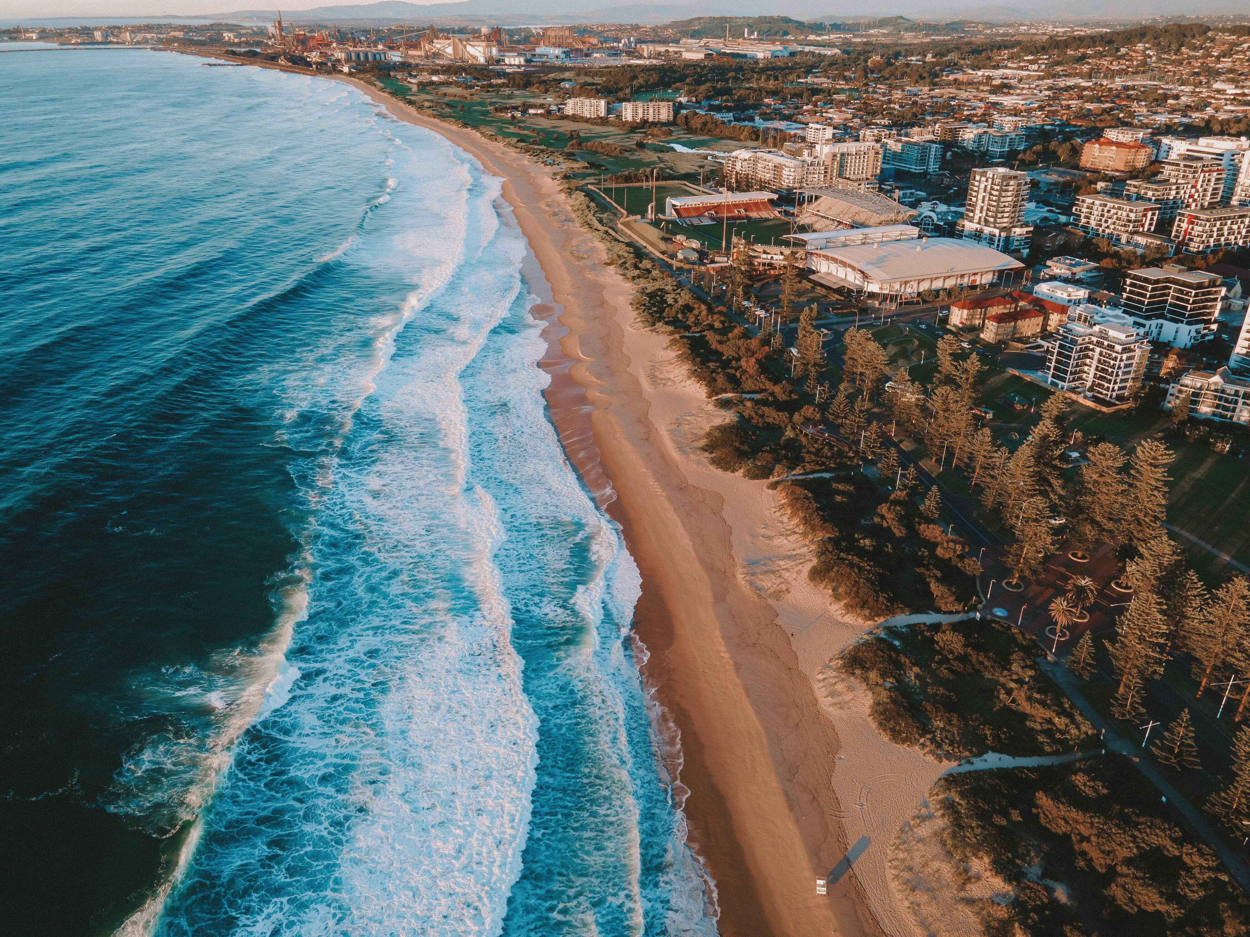 Aerial view of Wollongong's golden coastline and city skyline, a compelling summary for property buyers considering Wollongong suburbs in 2026.