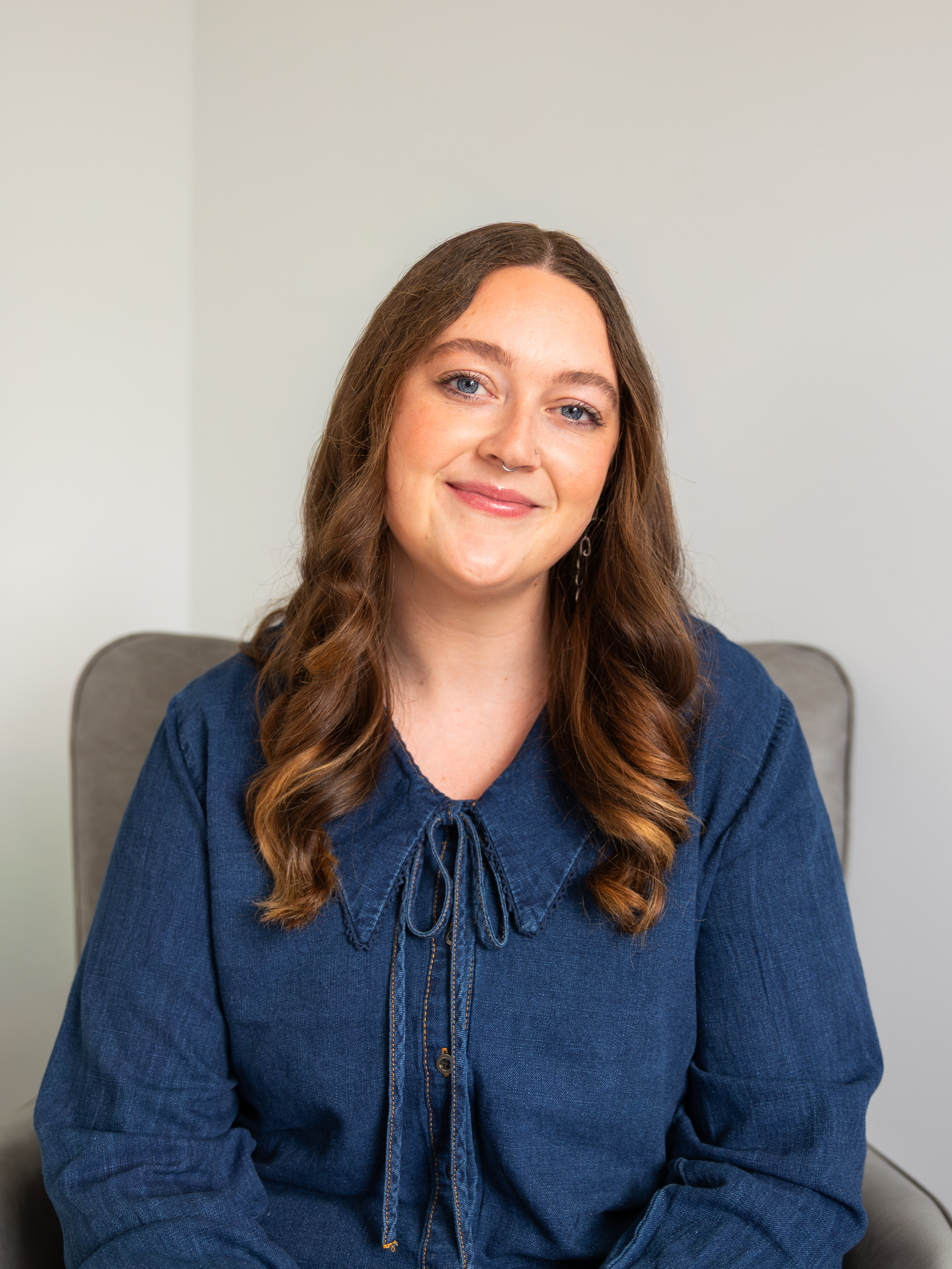 Tyler R. Hill, LMSW, smiling in a navy blue sleeveless shirt, showcasing tattoos, representing mental health counseling services at Connections Counseling Center, specializing in trauma, anxiety, and postpartum depression.