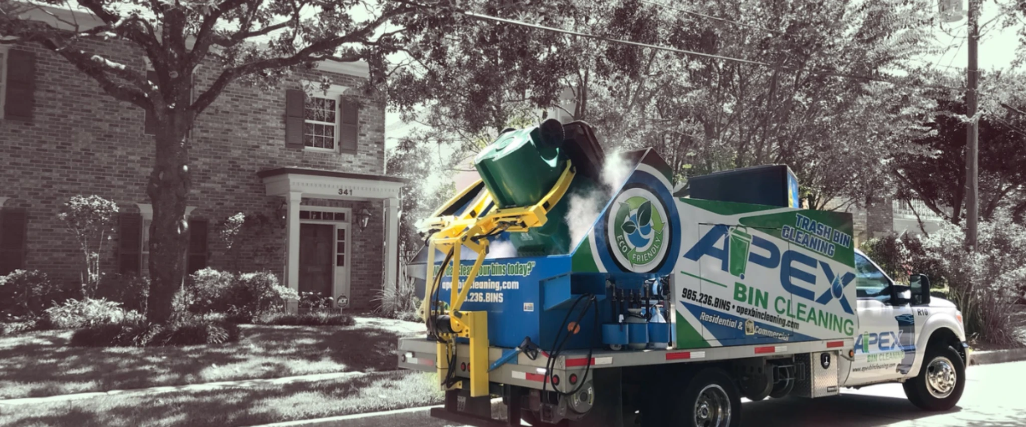 Mobile trash bin cleaning truck servicing residential garbage bins in a neighborhood. Mobile trash bin cleaning truck servicing residential garbage bins in a neighborhood.